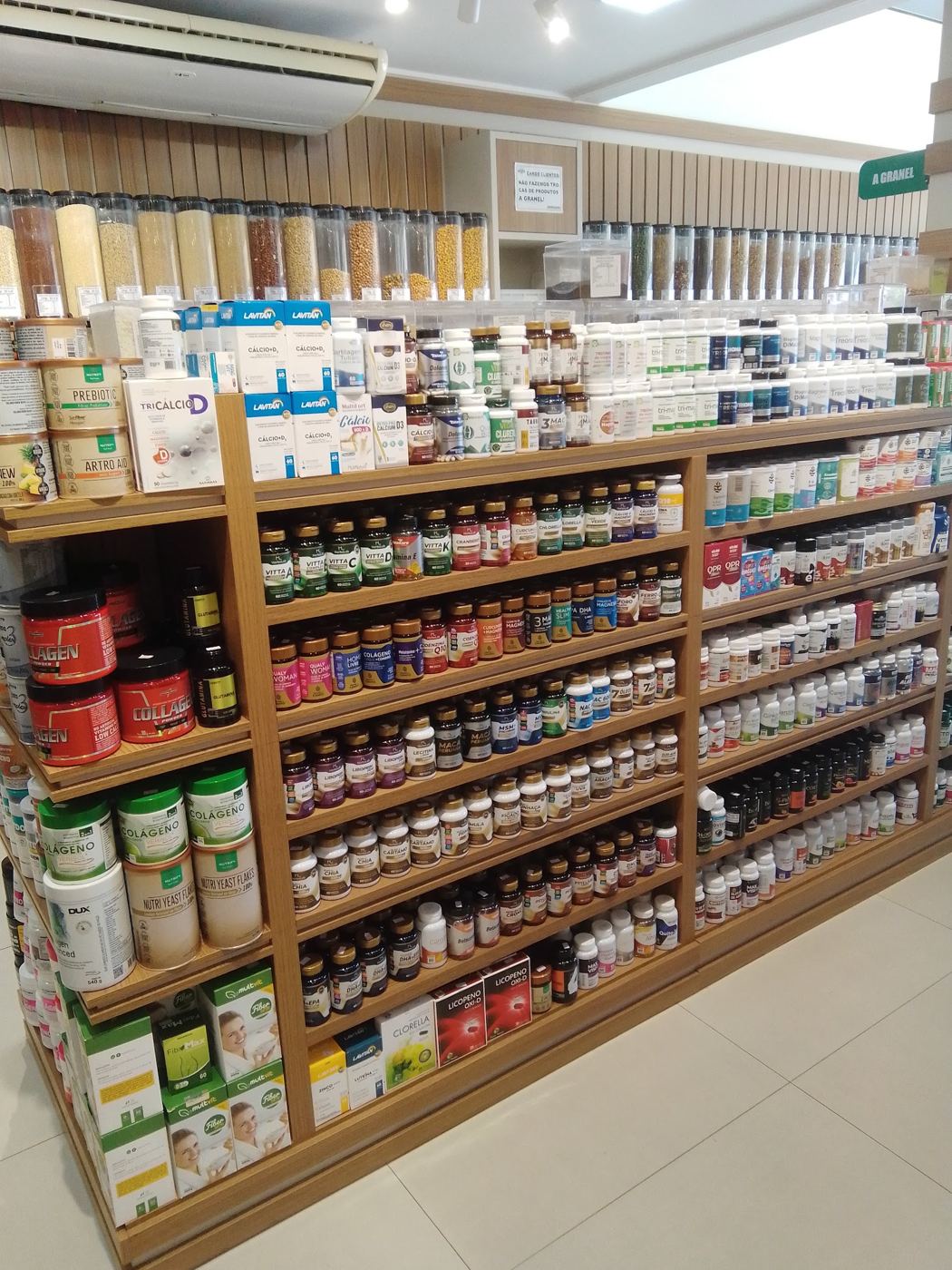 Prateleiras de madeira da Celeiro Natural com potes de granéis, vitaminas e alimentos naturais